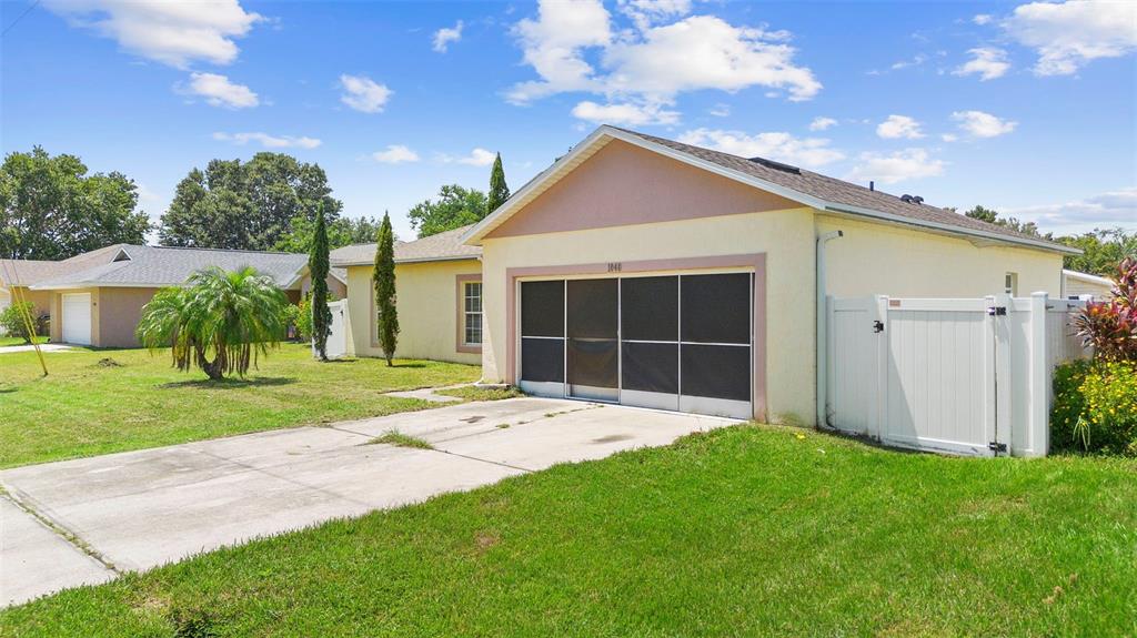 A single-story house with a screened-in garage, a concrete driveway, and a white vinyl fence — 1040 CANNOCK DRIVE, KISSIMMEE, FL