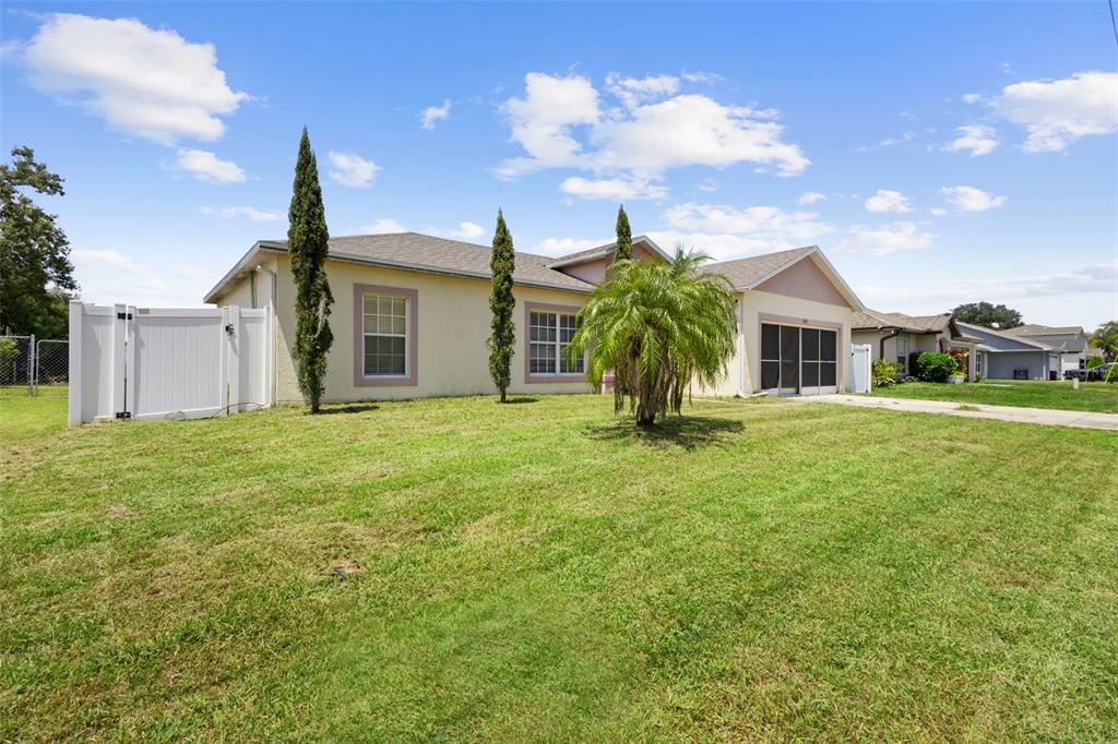 A single-story house with a beige stucco exterior, a garage, and a large front lawn — 1040 CANNOCK DRIVE, KISSIMMEE, FL