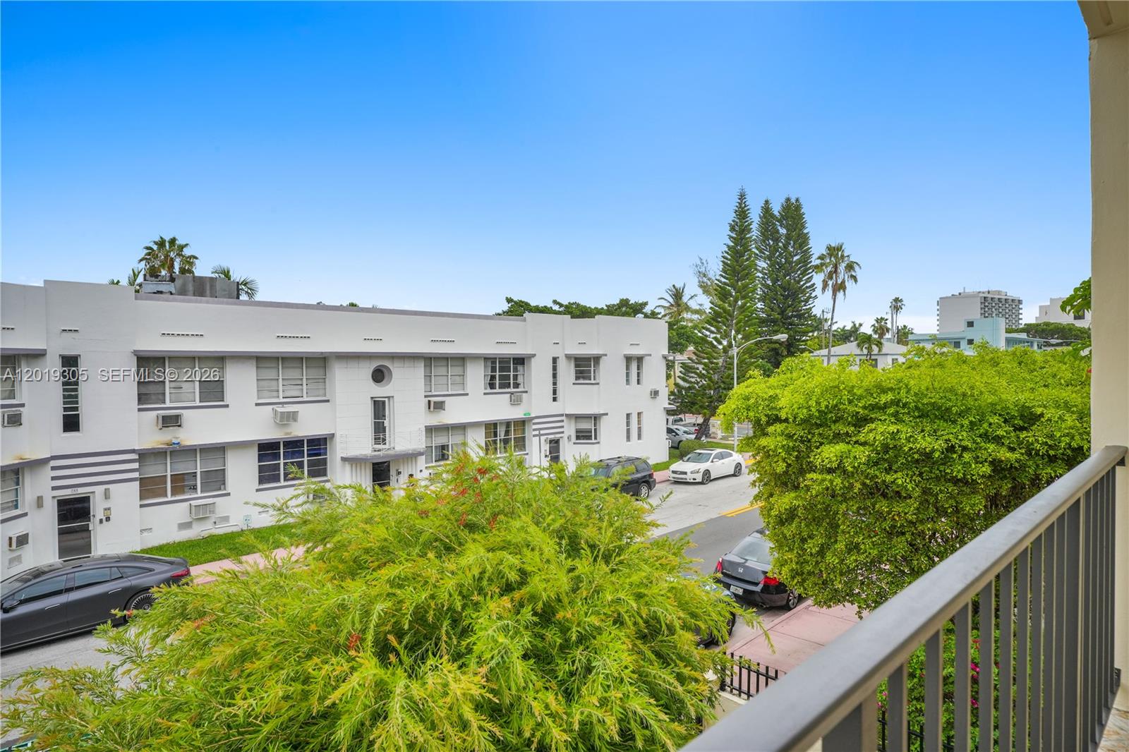 A view from a balcony overlooking a street, parked cars, and a white apartment building — 950 Euclid Ave # 201, Miami Beach FL 33139, MIAMI BEACH, FL