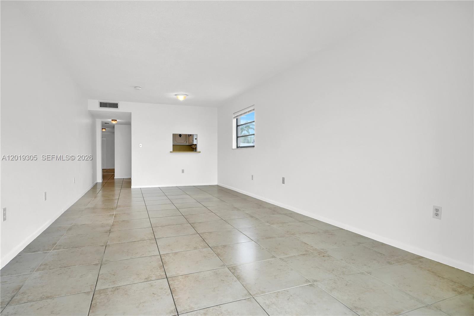 An empty room features white walls, light-colored tile flooring, and a small kitchen pass-through window — 950 Euclid Ave # 201, Miami Beach FL 33139, MIAMI BEACH, FL