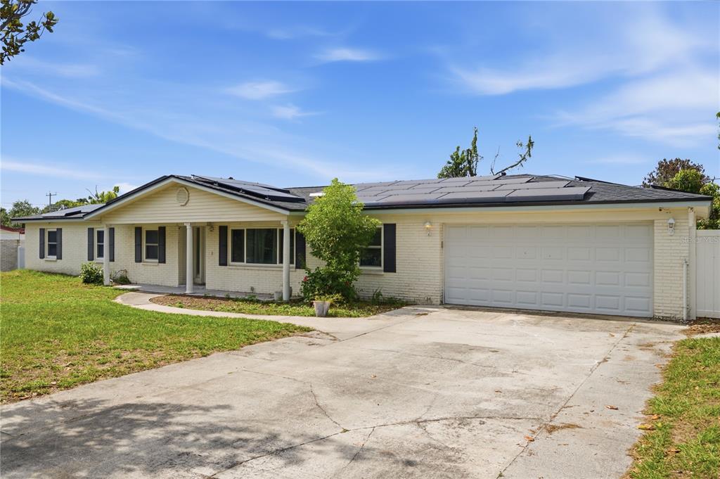 A single-story brick house with a white garage door, solar panels, and a concrete driveway — 1606 LARK LANE, BRANDON, FL