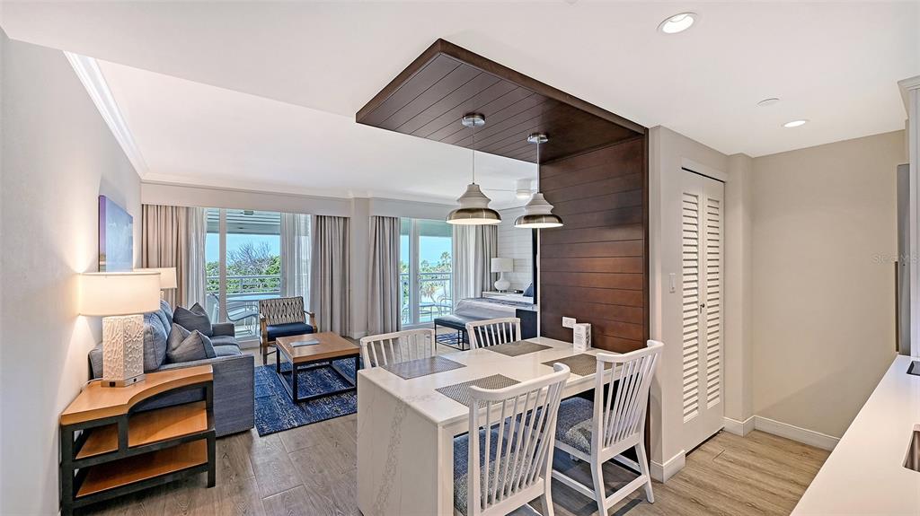 A living and dining area features a wood-paneled accent wall and a view of trees — 240 SANDS POINT ROAD UNIT 4205, LONGBOAT KEY, FL