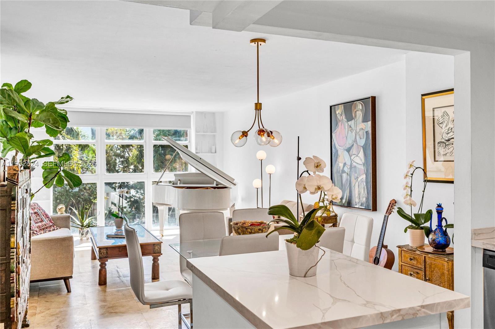 A bright living and dining area features a white grand piano and marble-topped island — 1228 West Ave # 209, Miami Beach FL 33139, MIAMI BEACH, FL