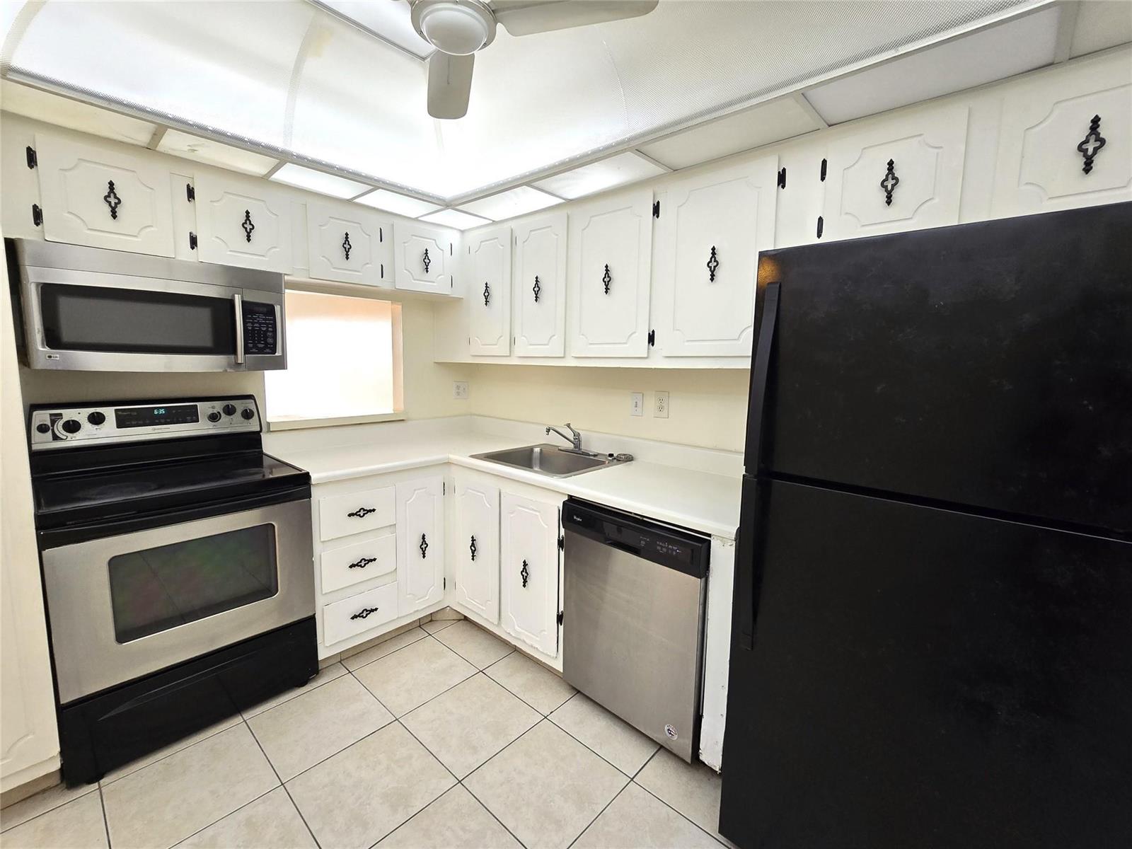 A kitchen features white cabinets, stainless steel appliances, a black refrigerator, and tiled flooring — 4334 NW 9th Avenue # 3B, Deerfield Beach FL 33064, DEERFIELD BEACH, FL