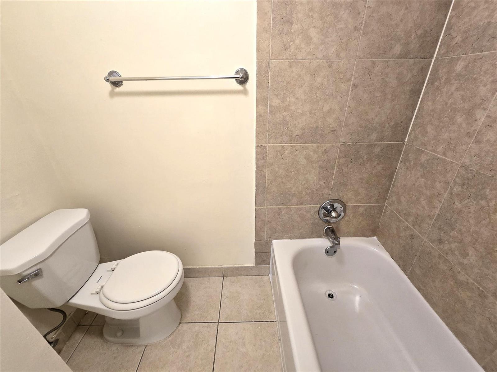 A bathroom features a white toilet, a bathtub with tiled walls, and a towel bar — 4334 NW 9th Avenue # 3B, Deerfield Beach FL 33064, DEERFIELD BEACH, FL