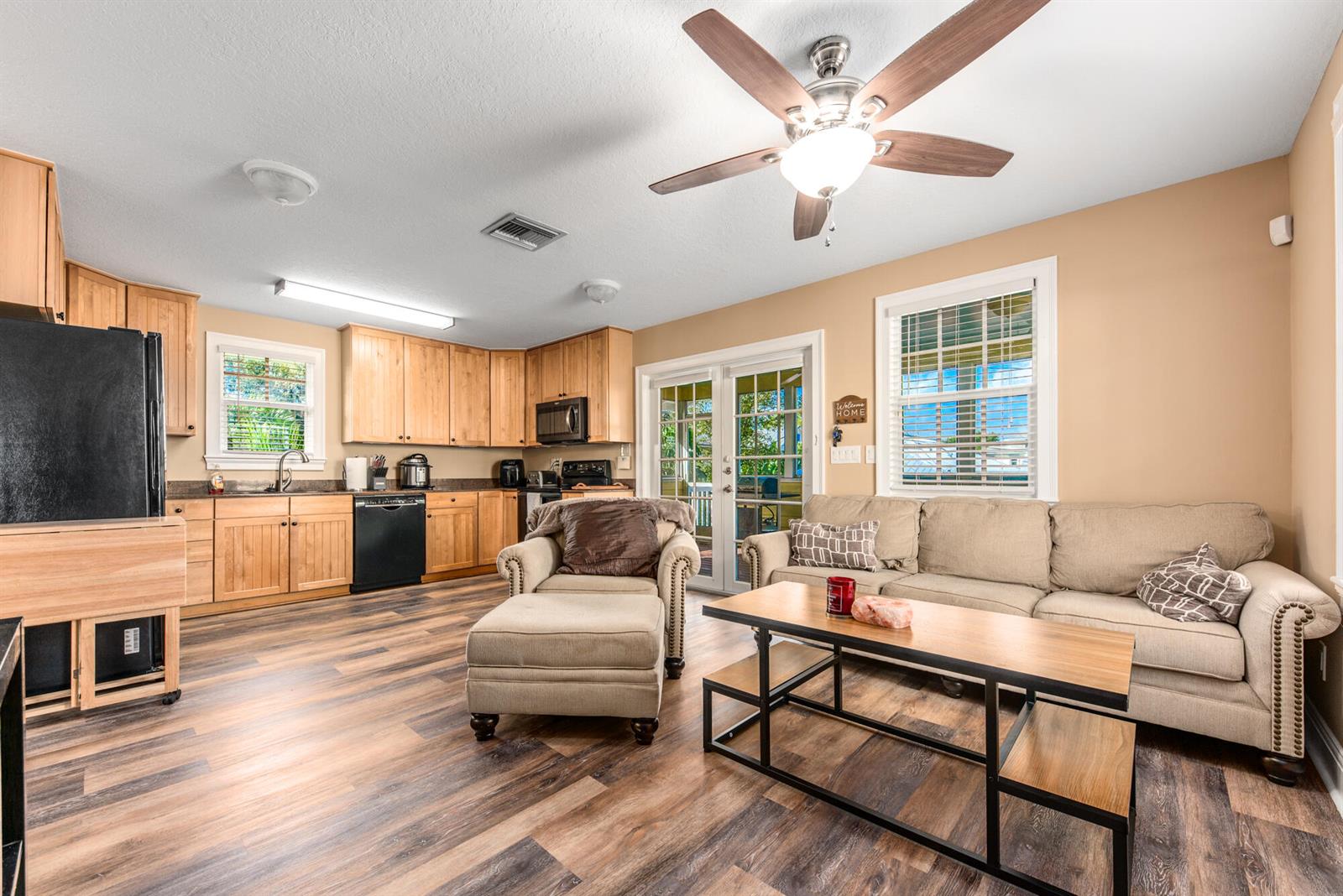 An open-concept kitchen and living room featuring light wood cabinets, wood-look flooring, and a sofa — 404 SW Camden Avenue, Stuart FL 34994, STUART, FL