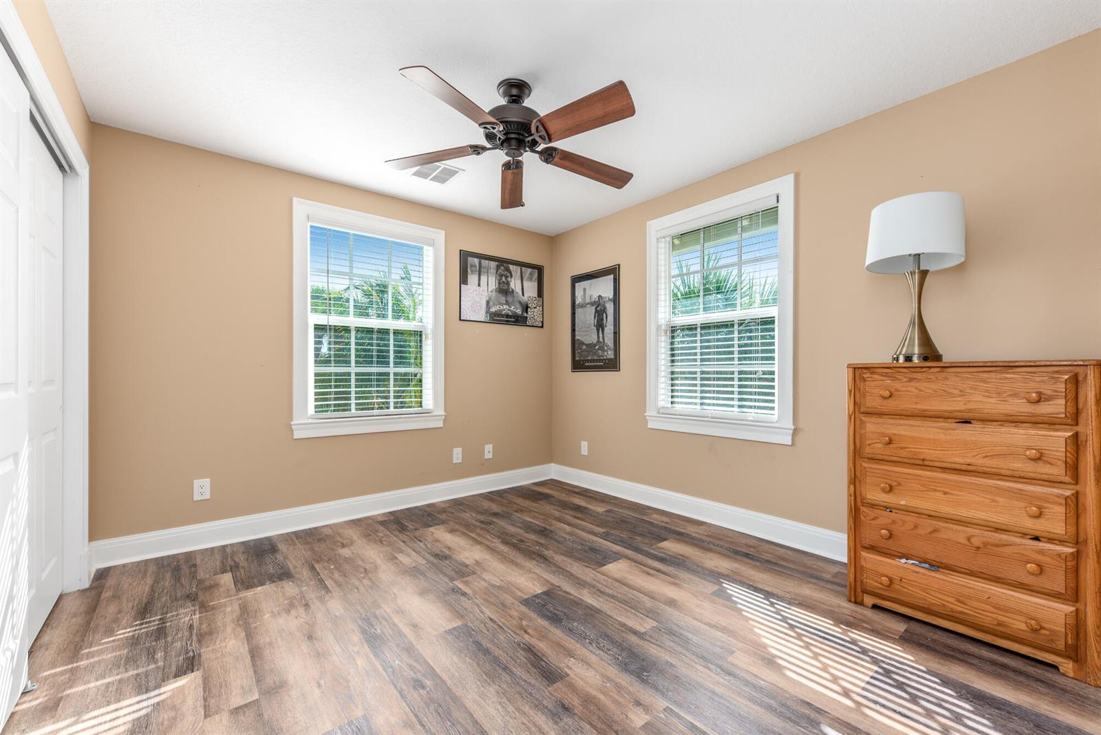 A bedroom features tan walls, wood-look flooring, a ceiling fan, and a wooden dresser — 404 SW Camden Avenue, Stuart FL 34994, STUART, FL