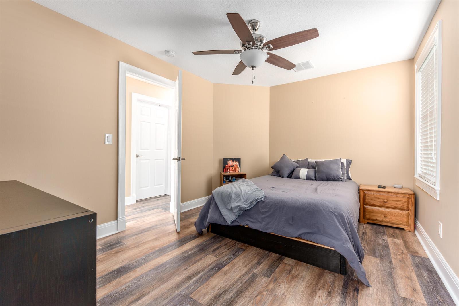 A bedroom features tan walls, wood-look flooring, a ceiling fan, and a queen-sized bed — 404 SW Camden Avenue, Stuart FL 34994, STUART, FL