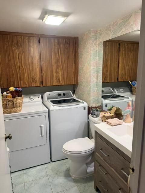 A laundry room features a washer, dryer, toilet, and wooden cabinets with a vanity sink — 319 3rd Way, West Palm Beach FL 33407, WEST PALM BEACH, FL