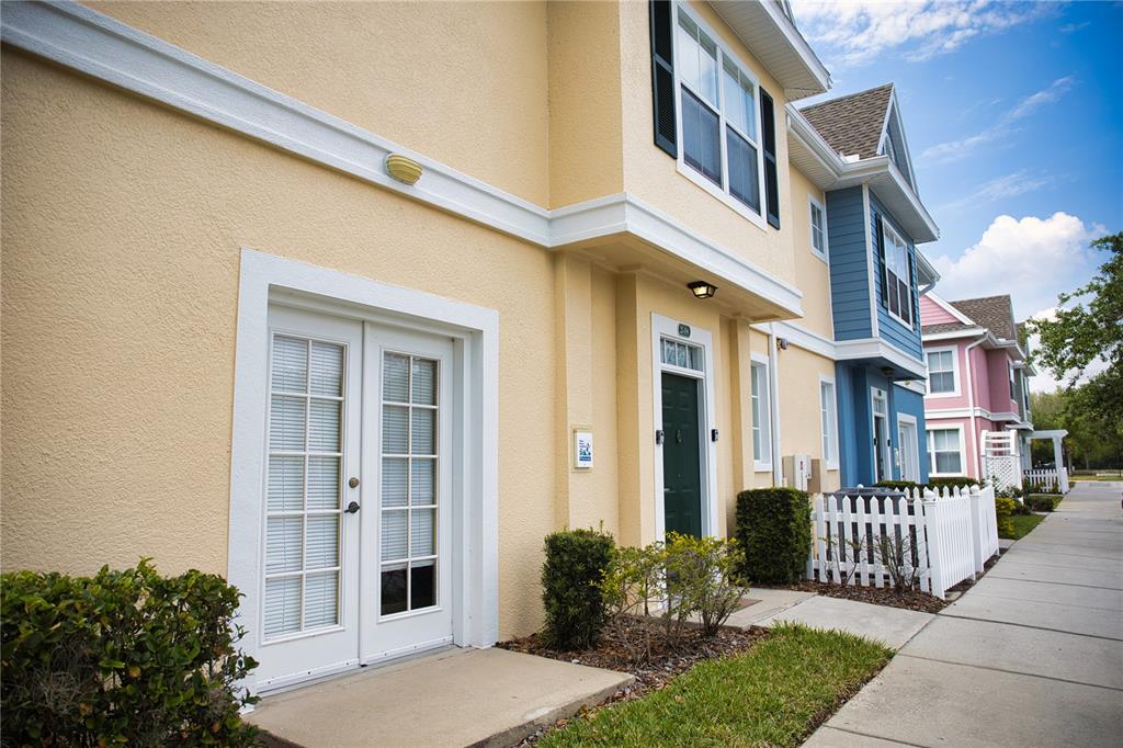 A row of colorful townhouses with a sidewalk and small front yards under a blue sky — 2205 SAN VITTORINO CIRCLE UNIT 104, KISSIMMEE, FL