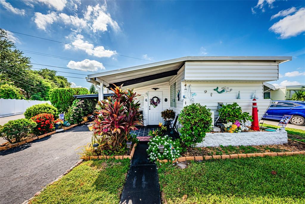 A single-story mobile home features a white exterior, a paved driveway, and landscaped front gardens — 4187 72ND STREET N UNIT 32, ST PETERSBURG, FL