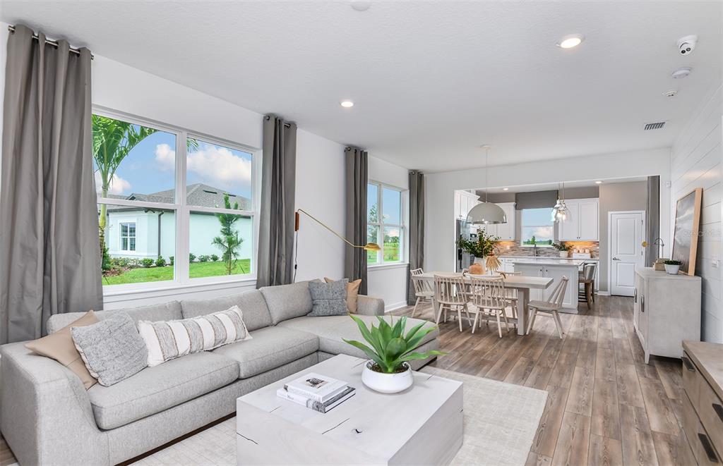 A living room with a grey sectional sofa, wood-look flooring, and an open-concept dining area — 5927 SW 87TH AVENUE, OCALA, FL