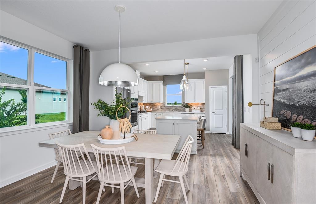 A dining area with a light wood table and chairs opens into a white kitchen — 5927 SW 87TH AVENUE, OCALA, FL