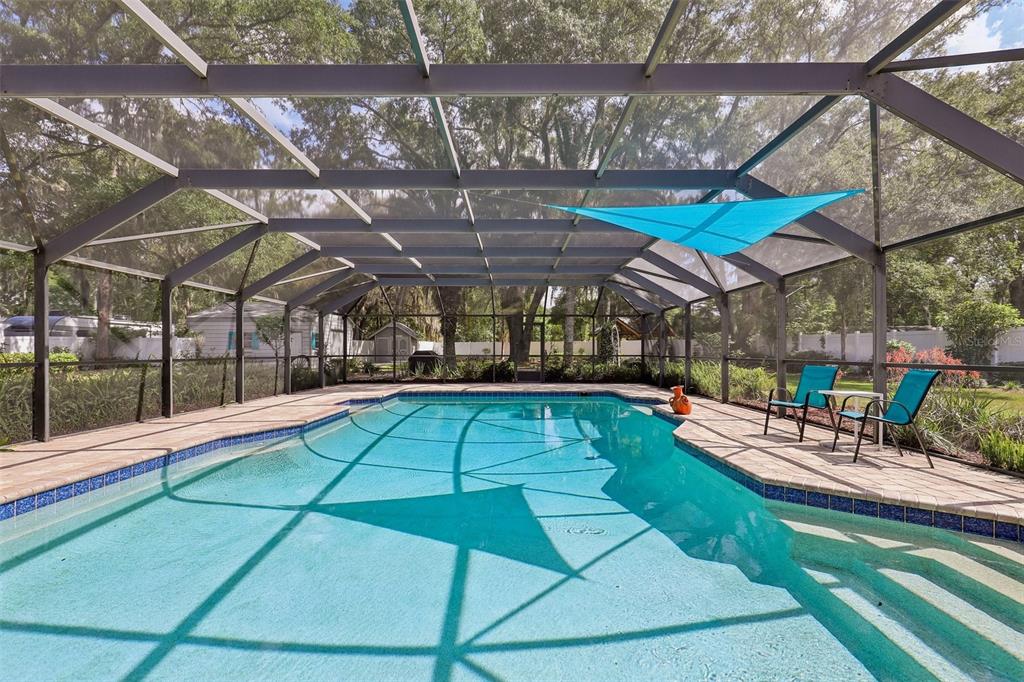 A swimming pool enclosed by a screened lanai with a blue shade sail overhead — 1590 PITCH PINE AVENUE, ST JOHNS, FL