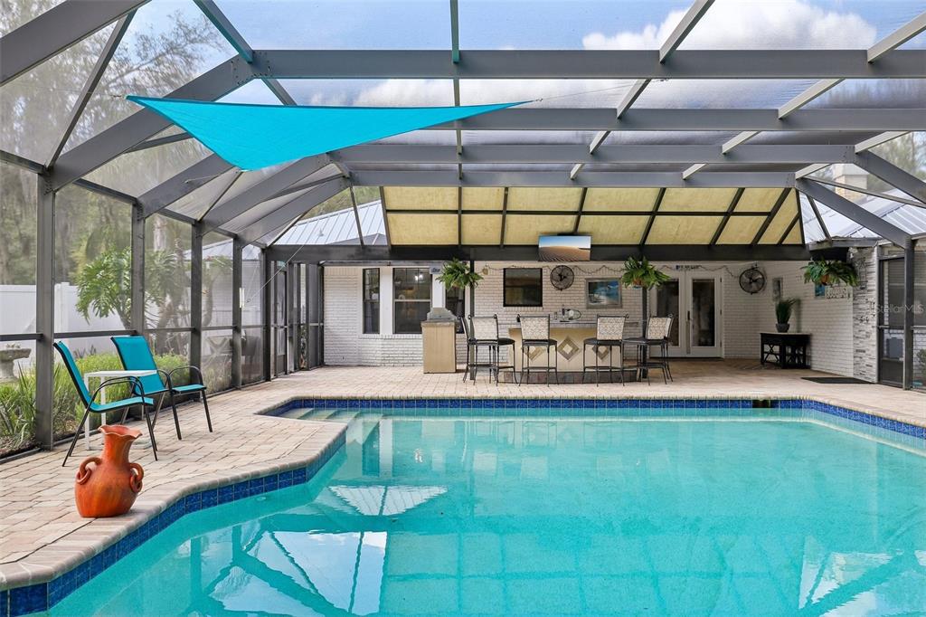 A screened-in patio features a swimming pool, a bar area, and outdoor seating — 1590 PITCH PINE AVENUE, ST JOHNS, FL