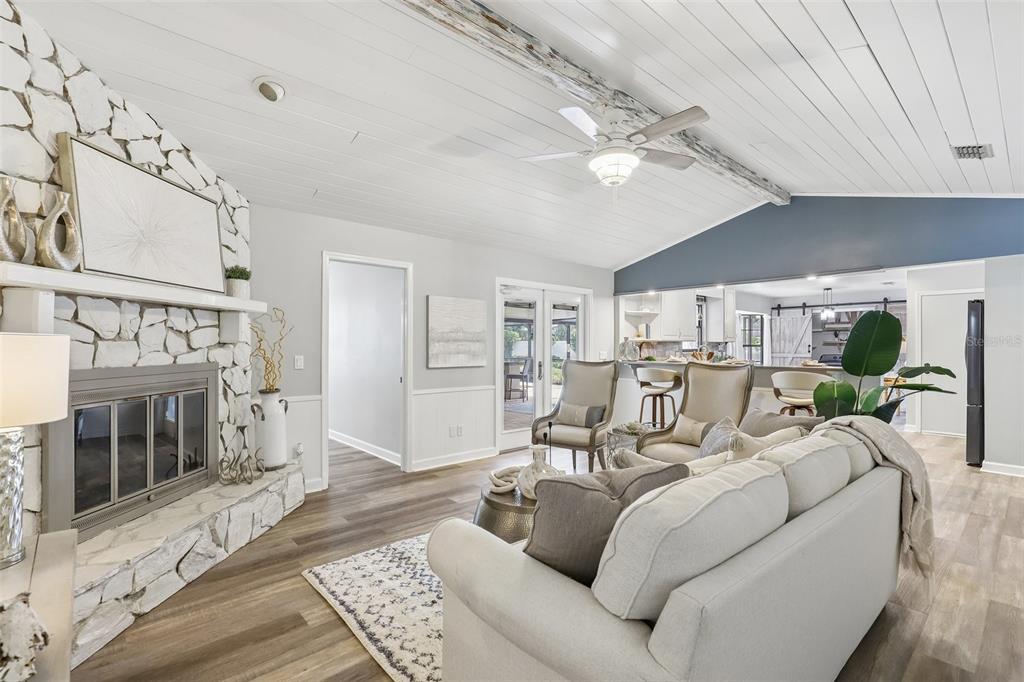 A living room features a stone fireplace, vaulted ceiling with a beam, and open kitchen — 1590 PITCH PINE AVENUE, ST JOHNS, FL
