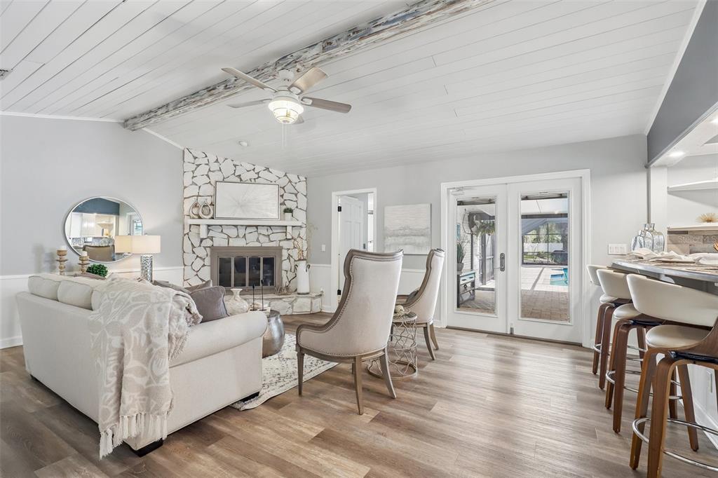 A living room features a stone fireplace, wood-look flooring, a ceiling fan, and patio doors — 1590 PITCH PINE AVENUE, ST JOHNS, FL