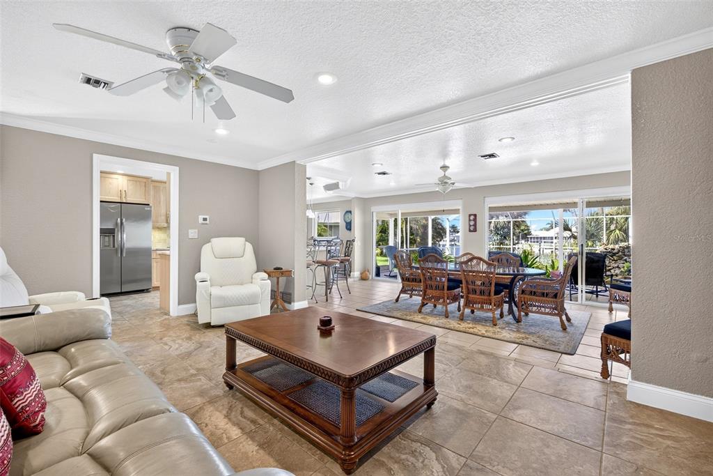 A living room with tile floors, a wooden coffee table, and an adjacent dining area — 401 NORMA COURT, PUNTA GORDA, FL