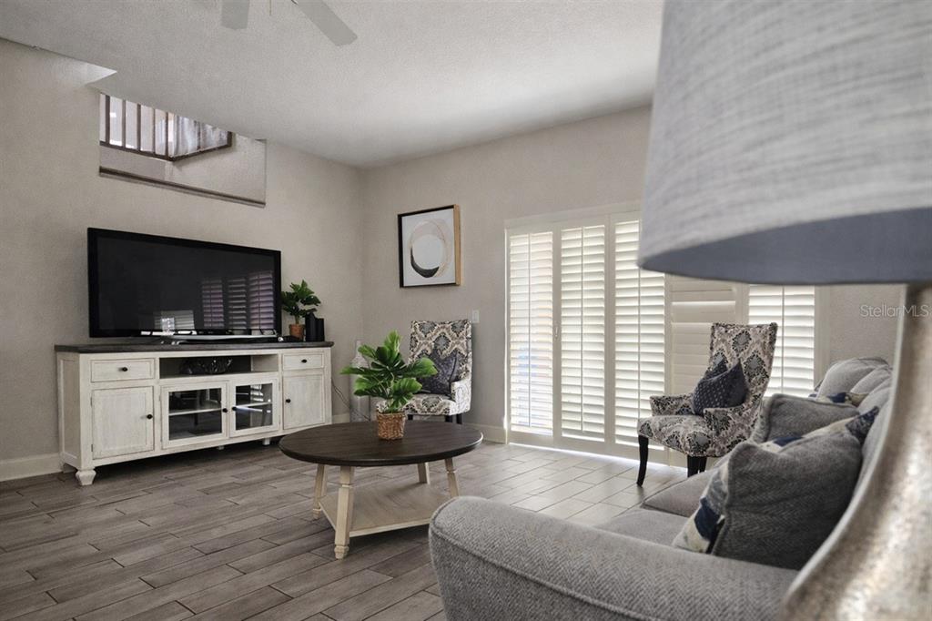 A living room features a television console, a round coffee table, and patterned armchairs — 3500 CALABRIA AVENUE, DAVENPORT, FL