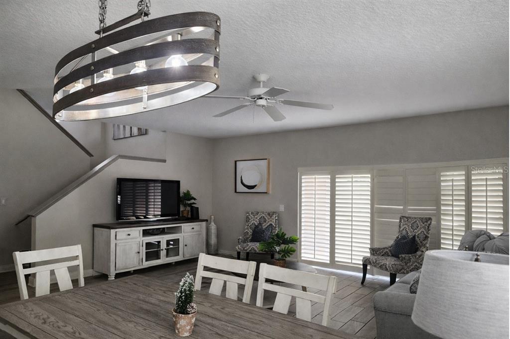 A living and dining area features a rustic chandelier, white furniture, and gray wood-look flooring — 3500 CALABRIA AVENUE, DAVENPORT, FL