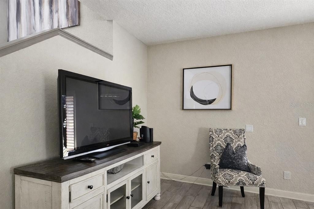 A living room features a television on a white media console and a patterned armchair — 3500 CALABRIA AVENUE, DAVENPORT, FL