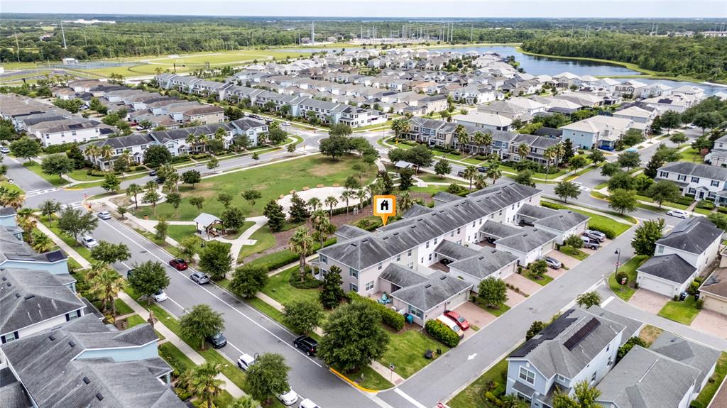 An aerial view shows a residential neighborhood with townhomes surrounding a central park area — 11574 COMIC ALLEY, ORLANDO, FL