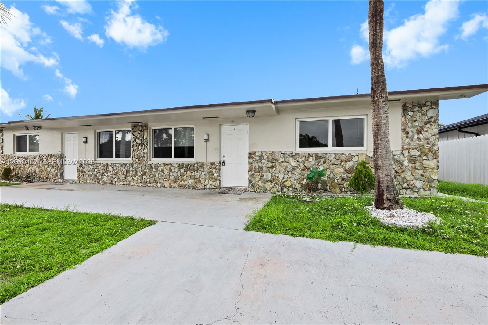 The exterior of a single-story building features stone veneer siding, white doors, and a concrete driveway — 1800 SW 97th Ave # A, Miramar FL 33025, MIRAMAR, FL