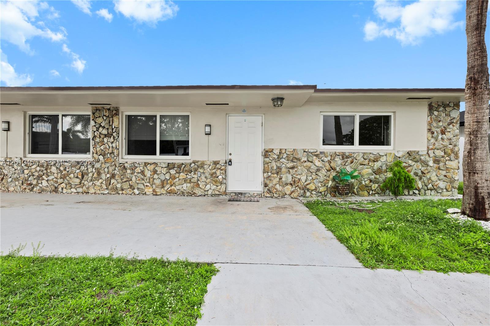 The exterior of a single-story house features a stone facade, white door, and concrete driveway — 1800 SW 97th Ave # A, Miramar FL 33025, MIRAMAR, FL