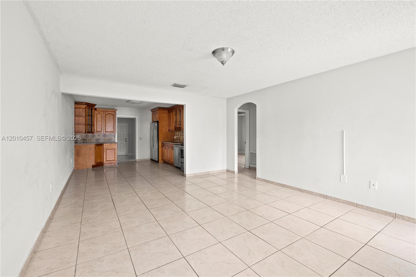 An open-concept living area features light-colored floor tiles, white walls, and a wood-cabinet kitchen — 1800 SW 97th Ave # A, Miramar FL 33025, MIRAMAR, FL