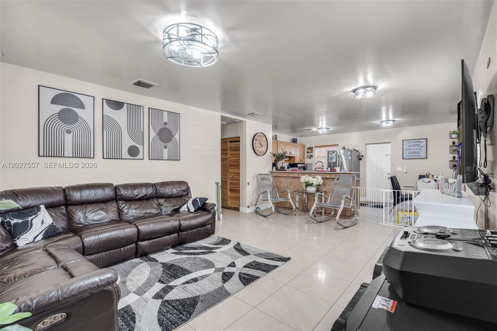 A living room features a brown leather sectional, tile flooring, and an open kitchen area — 2986 NW 26th St, Miami FL 33142, MIAMI, FL