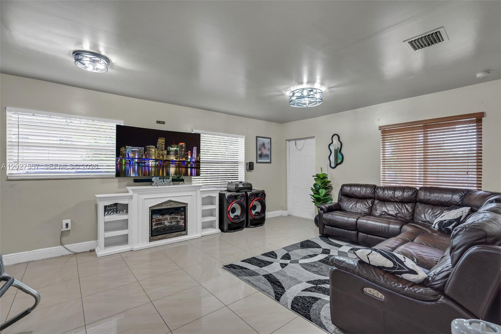 A living room features a fireplace, a wall-mounted television, leather furniture, and tile flooring — 2986 NW 26th St, Miami FL 33142, MIAMI, FL