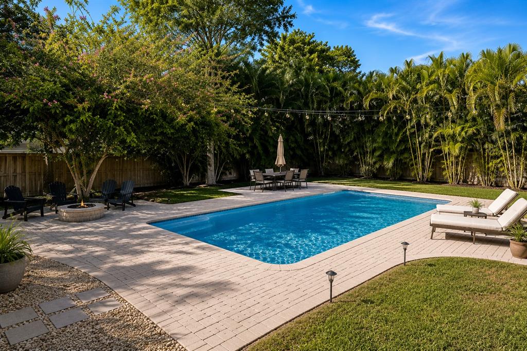 A backyard features a rectangular swimming pool, a stone patio, lounge chairs, and a fire pit — 220 45TH AVENUE S, ST PETERSBURG, FL