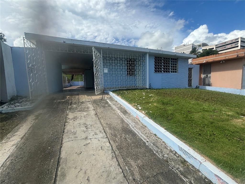 A light blue single-story house features a concrete driveway, a carport, and decorative metal grilles — 2 CALLE 2 VILLA RICA, BAYAMON, PR