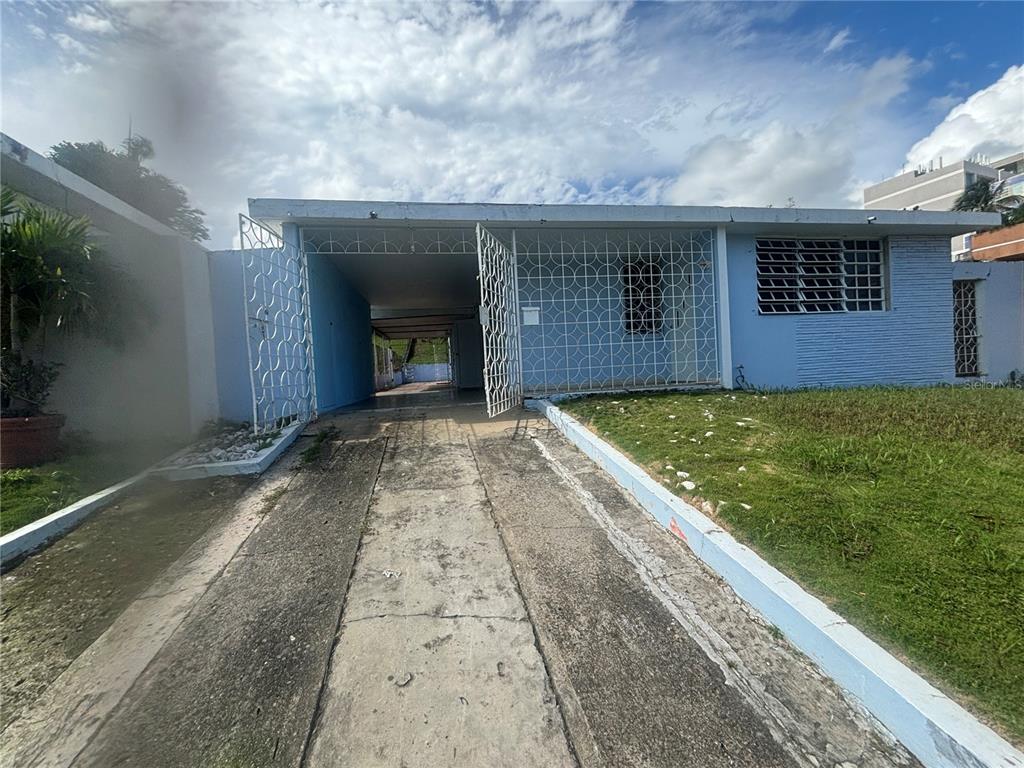 A light blue house with a driveway, a carport, and decorative white metal security grilles — 2 CALLE 2 VILLA RICA, BAYAMON, PR