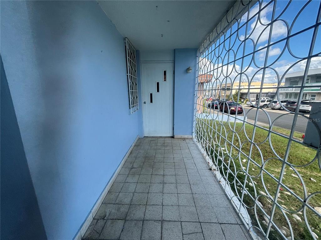 A covered porch with light blue walls, tiled flooring, and a white metal security gate — 2 CALLE 2 VILLA RICA, BAYAMON, PR
