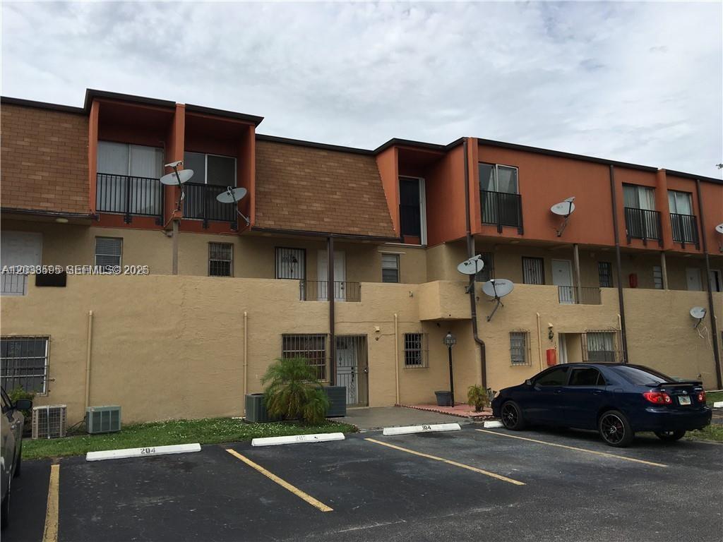 A two-story apartment building features tan stucco walls, orange upper accents, and a parking lot — 315 NW 109th Ave # 207, Miami FL 33172, MIAMI, FL