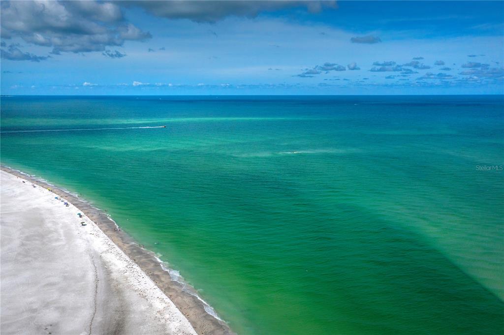 A stone sign for Neptune on Longboat Key stands before a multi-story blue building — 2850 GULF OF MEXICO DRIVE UNIT 5, LONGBOAT KEY, FL