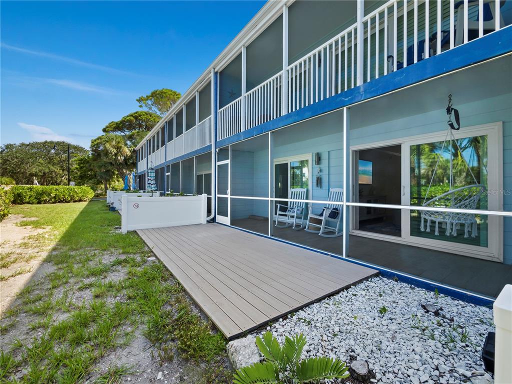 A kitchen features white cabinets, stainless steel appliances, light wood flooring, and a blue door — 2850 GULF OF MEXICO DRIVE UNIT 5, LONGBOAT KEY, FL