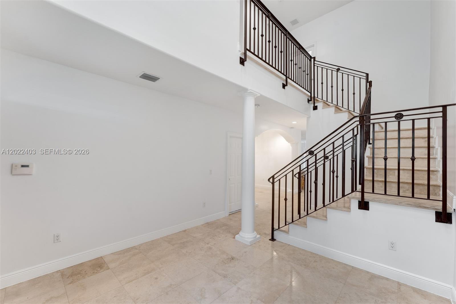 A bright foyer features a curved staircase with iron railings and beige tile flooring — 3060 Lime Ct # 3060, Miami FL 33133, MIAMI, FL