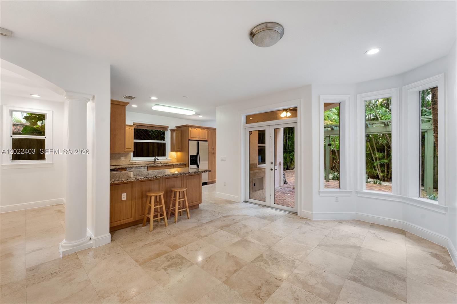 A kitchen with wood cabinets and a breakfast bar opens to a tiled dining area — 3060 Lime Ct # 3060, Miami FL 33133, MIAMI, FL
