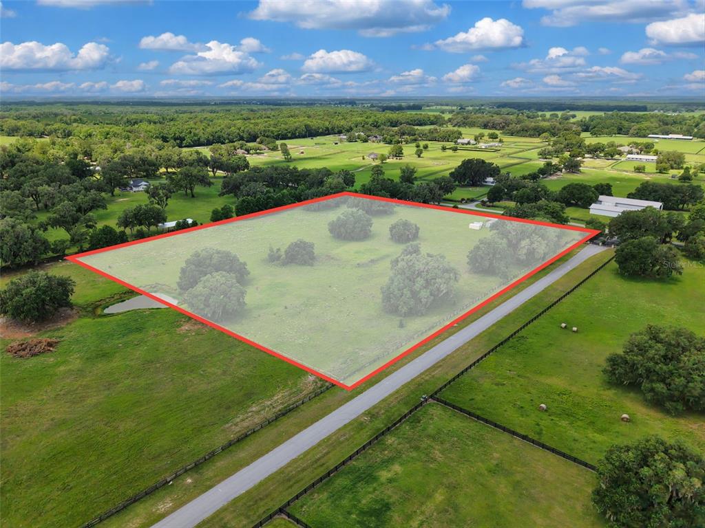 An aerial view shows a fenced, grassy plot of land highlighted by a red outline — Lot 10 NW 123RD LANE, MORRISTON, FL
