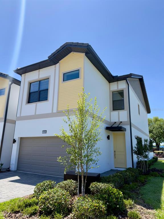 A two-story house with a beige garage, yellow accents, and a small front yard — 10592 EBB TIDE LANE, ORLANDO, FL
