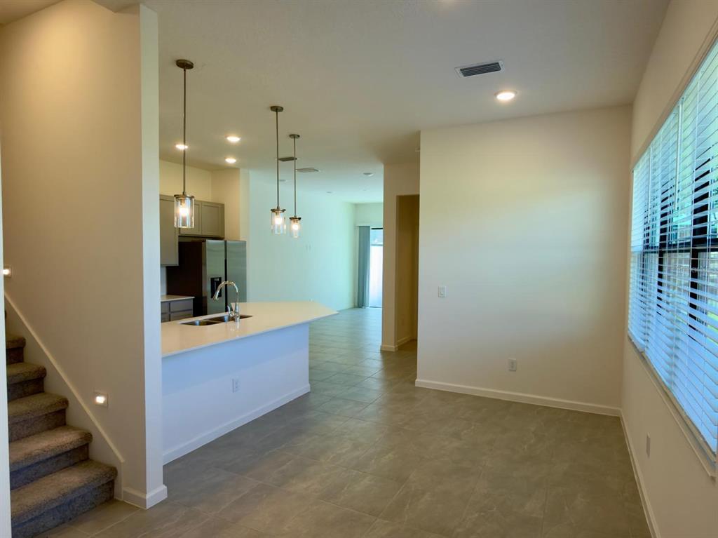 An open-concept kitchen with a breakfast bar overlooks a tiled dining area and staircase — 10592 EBB TIDE LANE, ORLANDO, FL