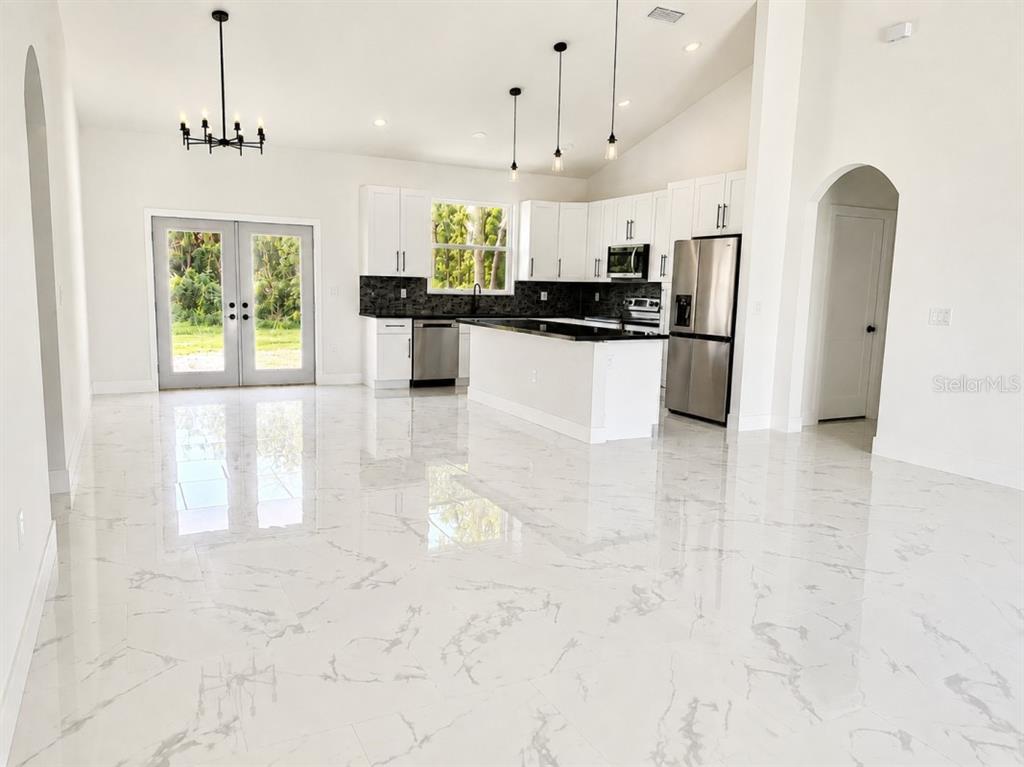 A modern kitchen with white cabinets, stainless steel appliances, and polished marble-look tile flooring — 3476 SE HWY 484, BELLEVIEW, FL