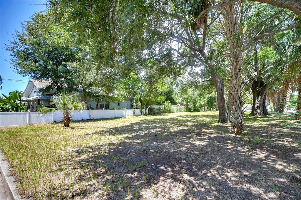 A grassy, tree-filled vacant lot is enclosed by a white vinyl fence — 1522 E 26TH AVENUE, TAMPA, FL