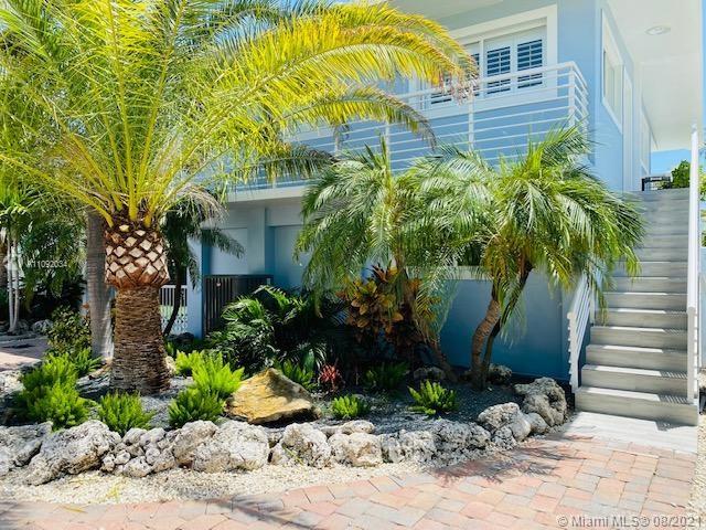 A light blue house features a palm tree, landscaping, and outdoor stairs leading to a balcony — 203 Atlantic Blvd # 203, Key Largo FL 33037, KEY LARGO, FL