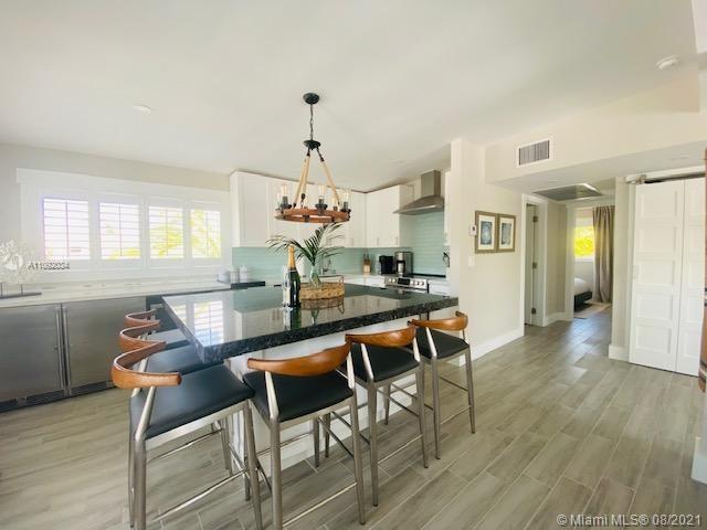 A kitchen features a dark granite island with bar stools, white cabinetry, and light flooring — 203 Atlantic Blvd # 203, Key Largo FL 33037, KEY LARGO, FL