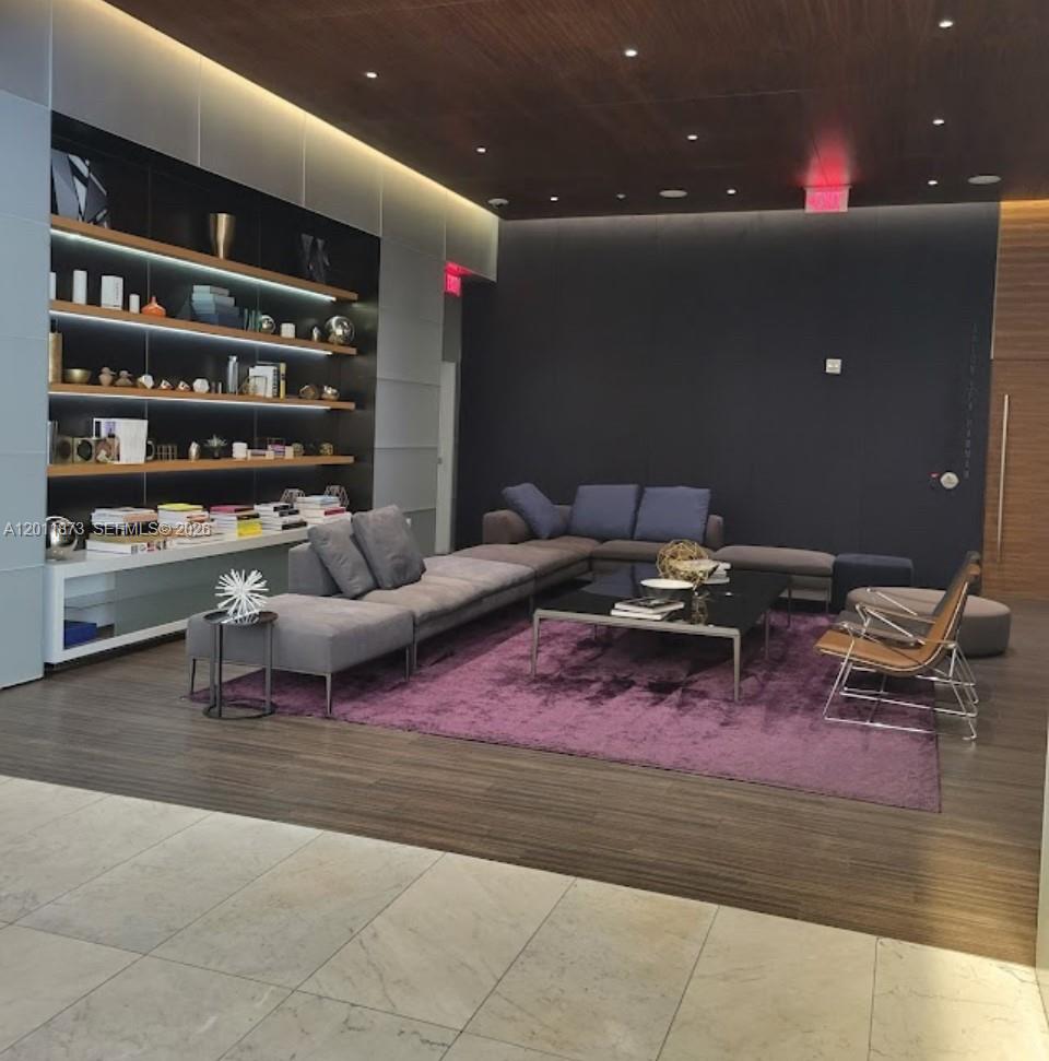 A modern lounge features a large gray sectional sofa, a purple rug, and built-in shelving — 88 SW 7 # 2112, Miami FL 33130, MIAMI, FL