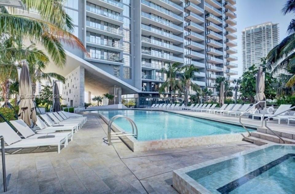 A swimming pool and hot tub are situated on a patio beside a modern building — 88 SW 7 # 2112, Miami FL 33130, MIAMI, FL