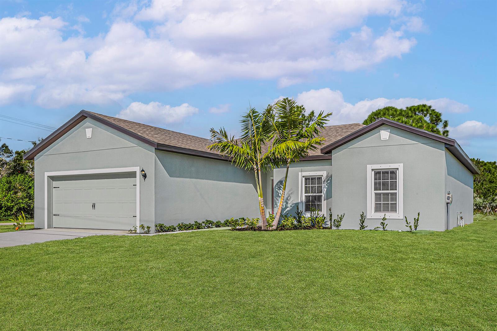 A light green single-story house with a two-car garage and a palm tree in front — 7945 105th Court, Vero Beach FL 32967, VERO BEACH, FL